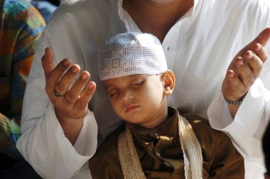 Çocuk, babasının dua ettiği gibi huzur içinde uyuyor; Bombay 'daki Anjuman İslam okulunda Ramzan Bayramı; Maharashtra; Hindistan