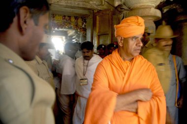 12 yılda bir düzenlenen Mahamastakabhishek festivali sırasında, turuncu cüppeli bir jain sadhu 'ya eşlik eden bir polis memuru, Shravanbelgola, Karnataka, Hindistan 