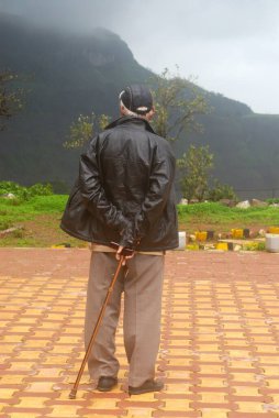 Malshej Ghat, Maharashtra, Hindistan 'da sisli duran yaşlı adam.