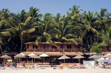 Turistler için ahşap kulübe şemsiyeleri Palolem Sahili Goa Hindistan Asya 