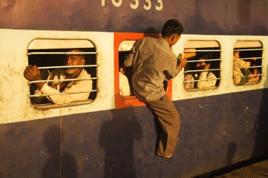Man coming out emergency window from train at ; surat railway station ; Gujarat  ; India clipart