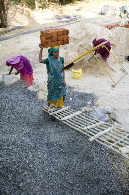 Ahmedabad, Gujarat, Hindistan 'da bir inşaat alanında kafasına tuğla taşıyan bir kadın. 