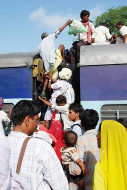 Tren istasyonundaki trenin çatısına tırmanmaya çalışan yaşlı adam; Jodhpur; Rajasthan; Hindistan