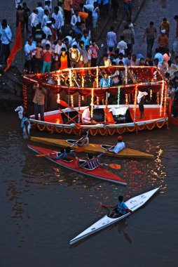Kayaks and decorated boat at river krishna during Ganesh immersion at Sangli  ; Maharashtra  ; India 7-September-2008 clipart