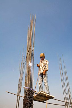 Ahmedabad, Gujarat, Hindistan şantiyesinde kasksız ve emniyet kemeri olmayan bir kaynakçı. 