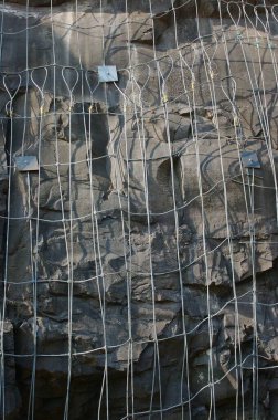 Konkan Demiryolu 'nun yanından Konkan, Maharashtra, Hindistan' a uzanan Konkan Demiryolu 'nu geçmek için kayalara çivilenmiş çelik tel örgüler.