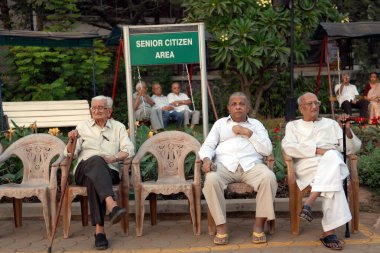 Bahçede, Mumbai 'de, Maharashtra' da, Hindistan 'da, Asya' da yaşlılar oturuyor. 