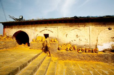 Devotee paying respects to statues immersed in turmeric powder at Jejuri temple, Pune, Phaltan, Maharashtra, India  clipart