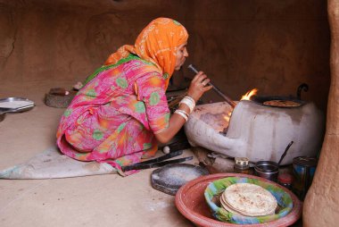 Ateşe körükle giden kadın yemek hazırlıyor Jodhpur, Rajasthan, Hindistan.