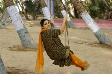 Hindistan cevizi ağacında sallanan kadın, Murud Janjira, Bölge Raigad, Maharashtra, Hindistan    