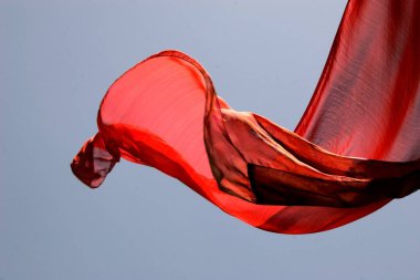 Hint geleneksel bayanların soyut kıyafetleri, kırmızı renkli sari olarak bilinir, rüzgardan dolayı mavi gökyüzünde uçarken çamaşır yıkadıktan sonra kurumak için asılır; Pune; Maharashtra; Hindistan