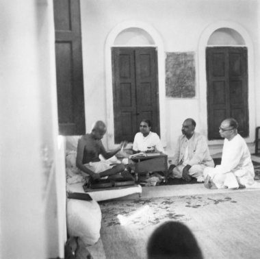 Mahatma Gandhi spinning and talking with Dr. Shyam Prasad Mukherjee and others at New Delhi, 1946, India   clipart