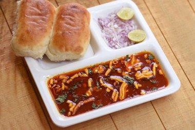 Indian delicious Misal Pav with onion and coriander spread on top of curry wheat bread clipart