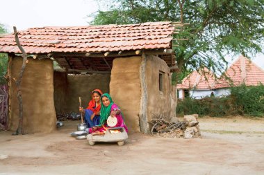 Kadınlar evlerinin dışındaki tahta ocakta yemek pişiriyorlar Kutch, Gujarat, Hindistan 