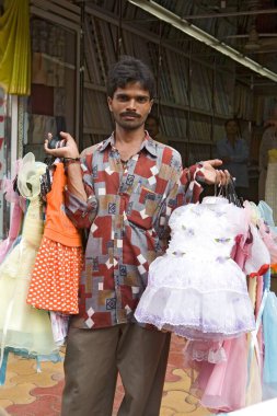 Bir seyyar satıcı elinde, Hindistan 'da Hindistan' da Mumbai Bombay, Maharashtra gibi yoğun bir yolda yürürken hazır bir grup çocuk elbisesi sergiliyor. 