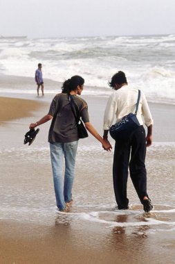 Erkek ve kadın deniz kıyısında yürüyorlar, Goa, Hindistan   