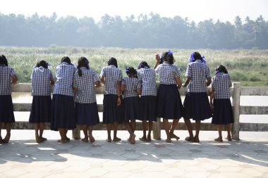 Adi Shankarachaya Tapınağı, Kaldi, Kerala, Hindistan 'da Poorna nehrinin kıyısında mavi gömlek ve etek giyen liseli kızlar. 
