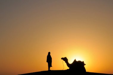 Kum tepelerinde deve, Jaisalmer, Rajasthan ve Hindistan 'da şanlı gündoğumu adamı.