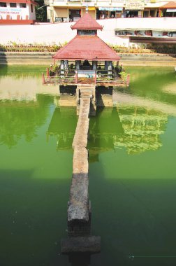 Temple in middle of pond and bridge made up of stone slab at ShriKrishna Math ; Udipi ; Karnataka ; India 5-May-2009 clipart