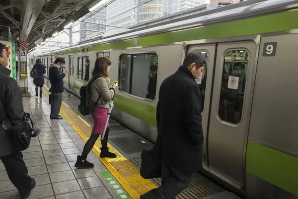 İnsanlar platformda, Tokyo 'da, Japonya' da tren bekliyor.  