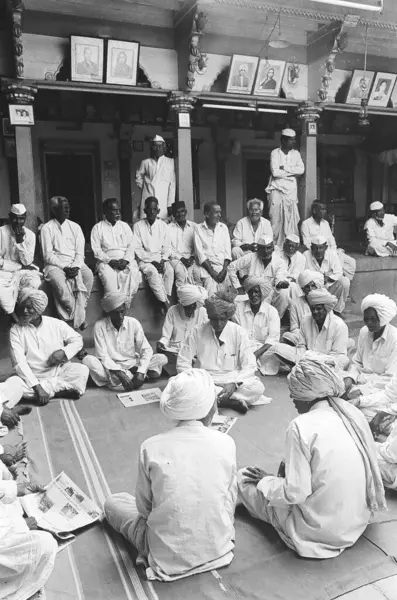 stock image Villagers of munagoli dressed in traditional white turbans or white caps gather in courtyard of old house of landlord to discuss village problems   