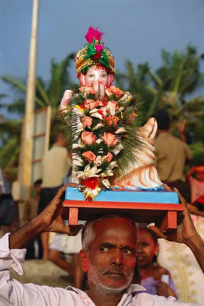 stock image man holding idol on his forehead On Ganesh ganpati Festival Elephant head Lord immersion , dadar , bombay mumbai, maharashtra , india