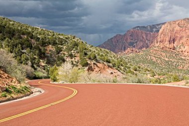 Kolob Kanyonu 'nun kırmızı kumtaşı dağları boyunca uzanan kırmızı bir yol; Zion Kanyonu Ulusal Parkı; Amerika Birleşik Devletleri