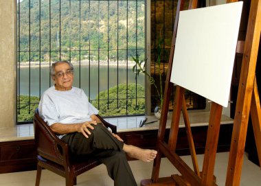Ünlü Hintli ressam Akbar Padasi stüdyosunda oturuyor.   