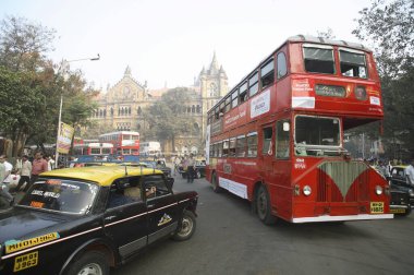 Indian street scene; local public transport Best red bus and black yellow color taxi; at Victoria terminus station building now renamed Chhatrapati Shivaji terminus; Bombay  Mumbai;  Maharashtra; India clipart