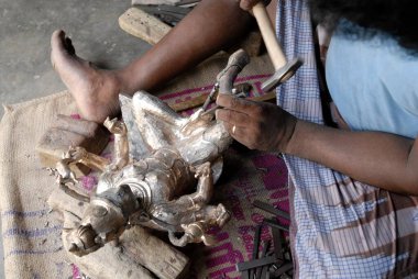 Heykeltraşlar keskiyle bronz simge oydular. 