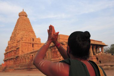 Hindu Brahmin doing namaste at Brihadeshwara Temple also called Big Temple dedicated to Lord Shiva built in 11th Century by Chola Empire located at head of Kaveri river delta; Thanjavur; Tamil Nadu; India UNESCO World Heritage Site clipart