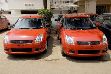 Sokakta iki kırmızı Suzuki Swift araba.