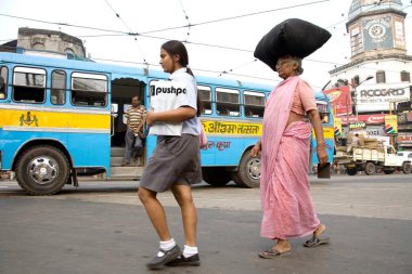 Street scene, school girl and old lady walking on road, Calcutta now Kolkata, West Bengal, India 