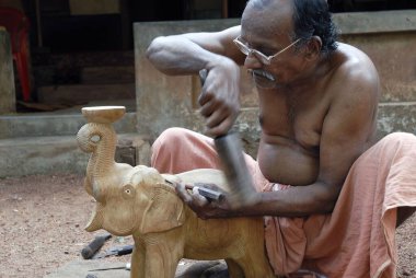 Thrissur, Kerala, Hindistan yakınlarında meşe ağacı fili oyan yaşlı bir adam. 