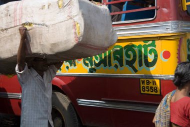 Howrah tren istasyonu ve yerel otobüs karmaşası trafiği yakınında kafasında yük taşıyan bir adam; Kalküta 'daki sokak sahnesi şimdi Kolkata; Batı Bengal; Hindistan;