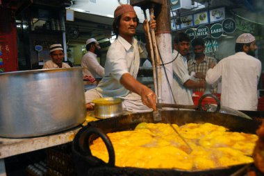 Müslümanlar, Pydhonie 'deki Khatri Mescidi' nde, Bombay 'da, Maharashtra' da, Hindistan 'da Ramzan veya Ramazan oruçlarını kırarken yemek hazırlayan bir gıda satıcısı.