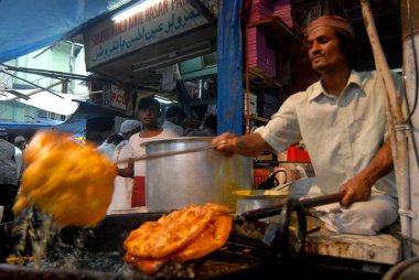 Müslümanlar, Pydhonie 'deki Khatri Mescidi' nde, Bombay 'da, Maharashtra' da, Hindistan 'da Ramzan veya Ramazan oruçlarını kırarken yemek hazırlayan bir gıda satıcısı.