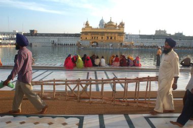 Amrit Sarovar 'ın mermer basamaklarında oturan Sikh nektar gölü, Altın Tapınak, Amritsar, Punjab, Hindistan 