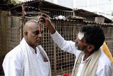 Tirumalai, Andhra Pradesh, Hindistan 'daki Balaji Tanrısı' nın alnına vishnu sembolü yapıştırmak.