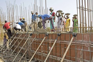 Construction workers engaged in the activity of filling concrete slab at a construction site in Ahmedabad, Gujarat, India  clipart