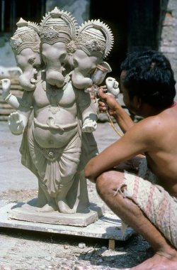 man doing spray painting on Lord Ganesh ganpati statue clipart