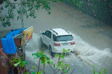Juhu Mumbai Hindistan Asya 'da su basmış yol musonu sezonunda araba hareket ediyor.