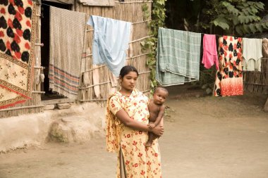 Kadın ve çocuk üzgün görünüyor. Bangladeş 'in Manik Gunj semtinde, küçük bir köyde, fakir bir hayat için kumaş asıyorlar. 