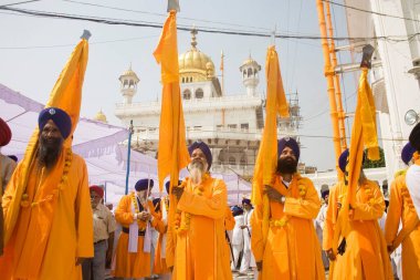 Orange color dressed Sikh men taking out the procession on the occasion of Guru Ramdas Jayanti out side Akal Takht, Swarn Mandir Golden temple, Amritsar, Punjab, India  clipart