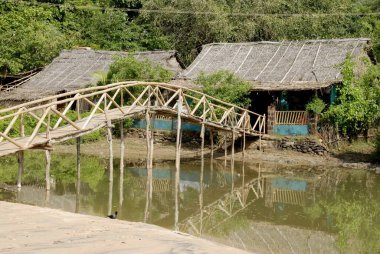 Om sahilindeki bambu köprüsü ile bağlanmış sazdan çatılı kulübeler; Kumta; Karnataka; Hindistan