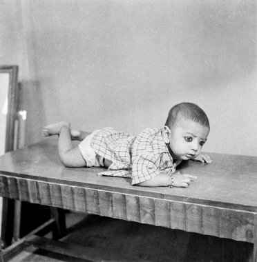 Eski tip 1900 'lerin siyah beyaz film stüdyosu Hindistan' da karın üstü yatan Hint bebek portresi.