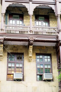 Balkon ve eski bir binanın kliması olan iki pencere; flora çeşmesi; Bombay Mumbai; Maharashtra; Hindistan