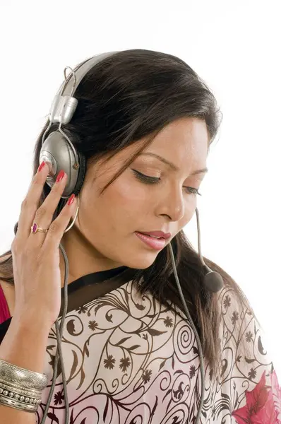 Güney Hintli kadın sari giyiyor ve beyaz stüdyo arka planında izole edilmiş müzik dinliyor.