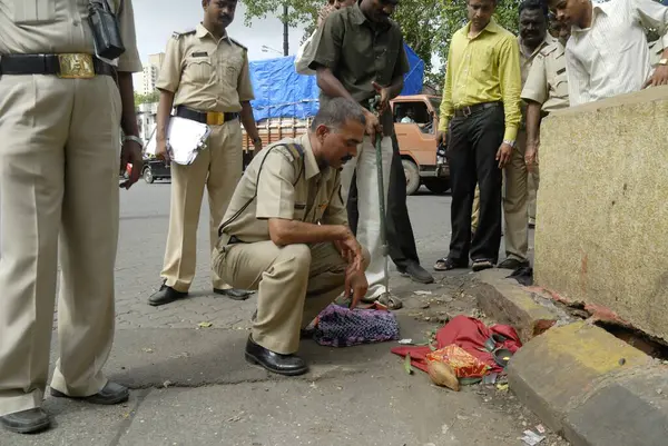 Bombay Mumbai, Maharashtra, Hindistan 'daki Chinchpokli istasyonu yakınlarında işlenmemiş bir bomba olduğu şüphesiyle polis personeli kimliği belirsiz bir paketi inceliyor.   