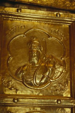 Guru Gobind Singh embossed on gold leaf fitted on door of Sachkhand Sahib Gurudwara , Nanded , Maharashtra , India clipart
